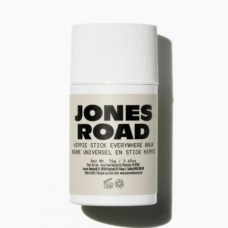 Jones Road Hippie Stick balta serumo lazdelė su smėlio spalvos etikete baltame fone