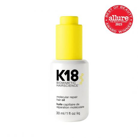 Mini bottiglia bianca di olio per capelli K18 Molecular Repair con moderno tappo contagocce giallo su sfondo bianco con sigillo rosso Allure BoB nell'angolo in alto a destra