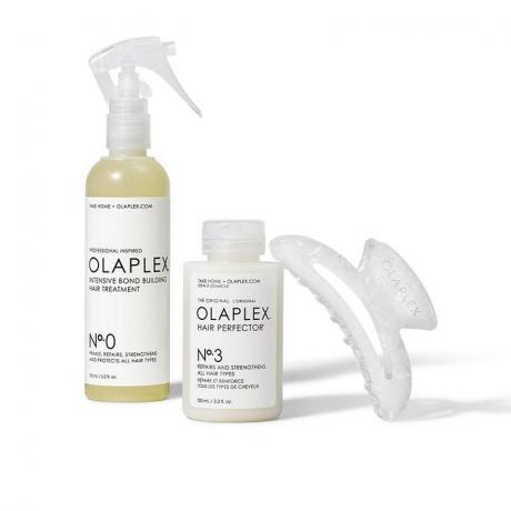 Olaplex The Ultimate Repair Kit: белый распылитель, флакон с крышкой и зажим для волос на белом фоне.