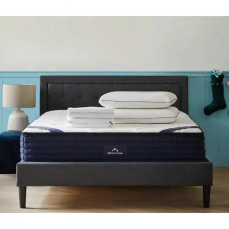 DreamCloud prabangus hibridinis čiužinys su pagalvėmis ir sulankstytais paklodėmis miegamajame su mėlyna siena