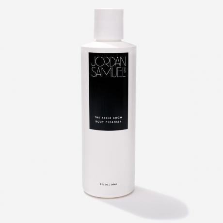 Sticla albă de Jordan Samuel After Show Body Cleanser pe un fundal gri deschis, aproape alb. Eticheta de pe sticlă este neagră