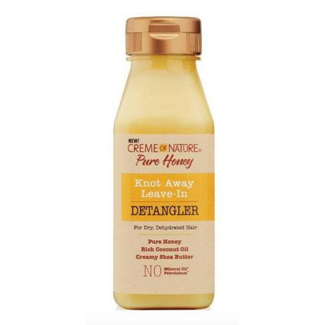 Прозрачная бутылка крема для расчесывания Creme of Nature Knot Away желтого оттенка на белом фоне.