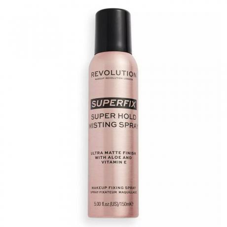 Makeup Revolution Superfix Misting Spray زجاجة بخاخة من الذهب الوردي مع غطاء أسود على خلفية بيضاء