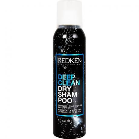 Kaleng semprot aerosol hitam dengan desain percikan putih dan teks biru dan putih dari Redken Deep Clean Dry Shampoo pada latar belakang putih.
