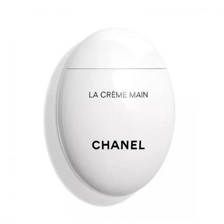 Бяла яйцевидна бутилка Chanel La Crème Main на бял фон
