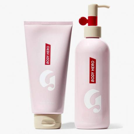 Glossier Body Hero Duo Atur botol pompa dan botol peras berwarna merah muda dengan latar belakang abu-abu