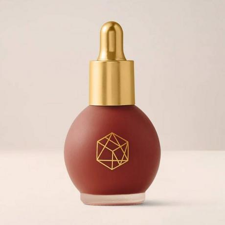 Em Cosmetics Color Drop Serum Blush vial redondo de rubor líquido de bayas parduscas con tapa dorada sobre fondo beige