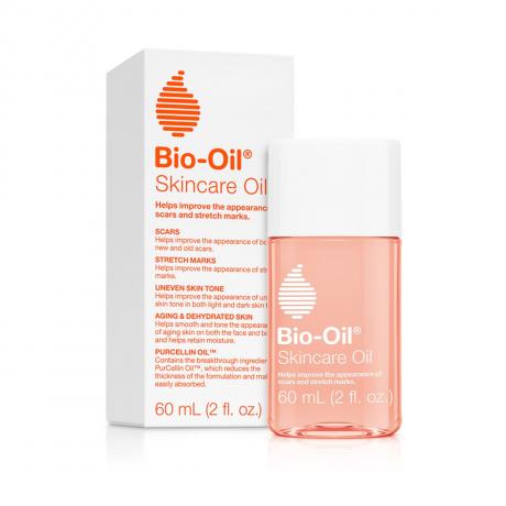 Botol berwarna peach bening dengan tutup putih dan tulisan " Bio-Oil Skincare Oil" dengan kotak kemasan yang serasi dengan latar belakang putih.