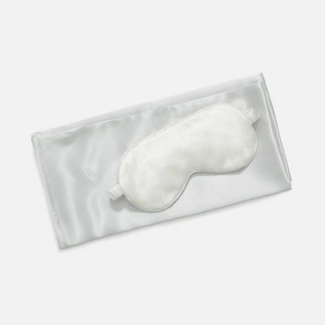 „Brooklinen Mulberry Silk Bundle“: baltas pagalvės užvalkalas ir atitinkama akių kaukė pilkame fone