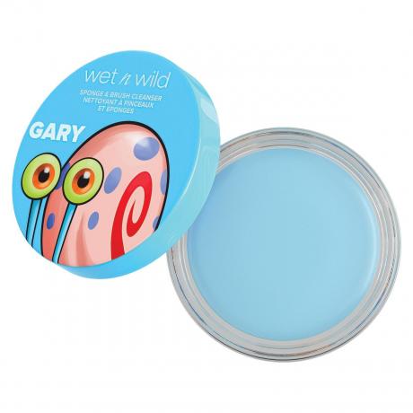 Um frasco aberto azul de Wet n Wild Gary, o caracol, espuma de sabão, esponja e escova de limpeza em fundo branco