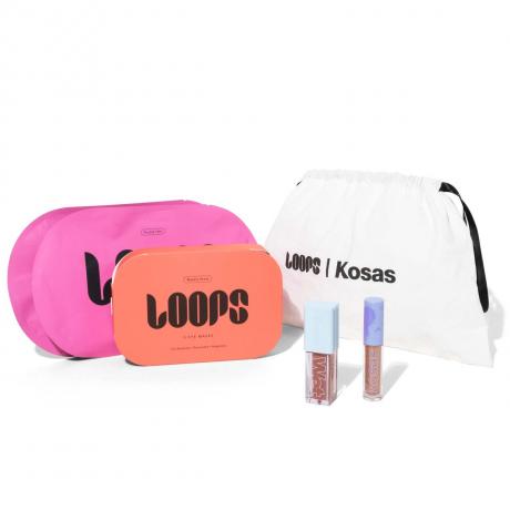 Kosas X Loops Glow Up Set sachets de masque facial rose et orange, deux tubes de brillant à lèvres et un sac à cordon blanc sur fond blanc