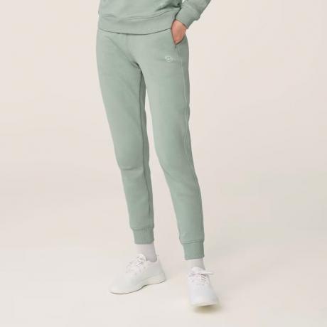 Modèle Allbirds R&R Sweatpant portant un pantalon de survêtement vert clair sur fond beige