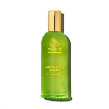 Tata Harper Hydrating Floral Essence: En grønn glassflaske med gul tekst og en gullhette på hvit bakgrunn