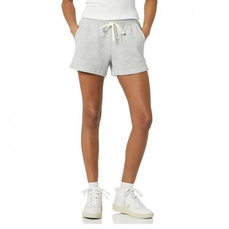 Una persona modelando el pantalón corto de forro polar para mujer Amazon Essentials sobre un fondo blanco.