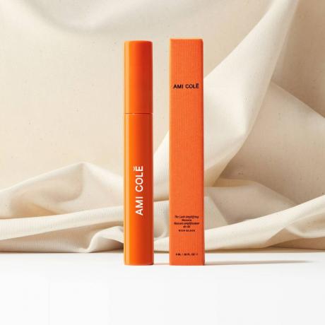 en orange tub Ami Colé fransförstärkande mascara bredvid sin ask. I bakgrunden är en elfenbensduk typ skrynklig men på ett konstnärligt sätt