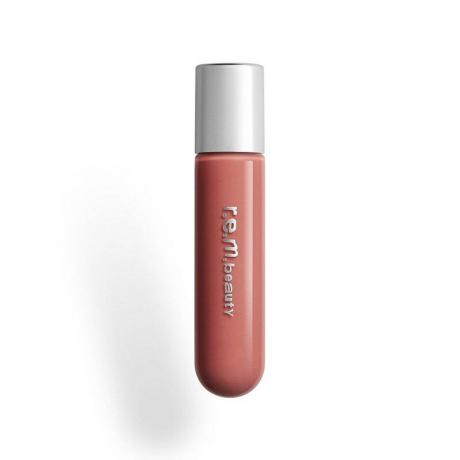 Um tubo transparente do r.e.m. beauty On Your Collar Plumping Lip Gloss em tom rosa nude Scrunchie em um fundo branco