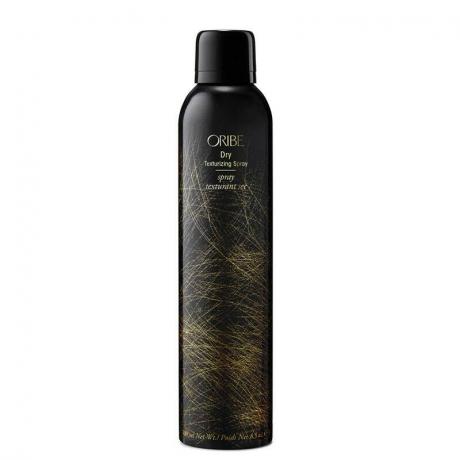 Une bouteille noire et dorée de l'Oribe Dry Texturizing Spray sur fond blanc
