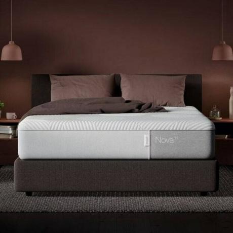 Loş bir yatak odasında gri bir karyola üzerinde Casper Nova Hibrit Yatak (Kraliçe).