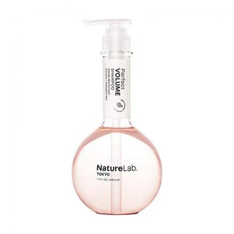 O sticlă transparentă de șampon de la NatureLab roz. Sampon Tokyo Perfect Volume pe fundal alb