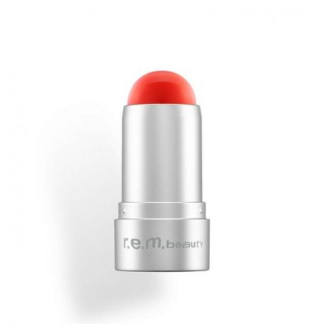 Un petit tube en argent du R.E.M. beauté Eclipse Lip & Cheek Stick dans une teinte rouge vif Leading Lady
