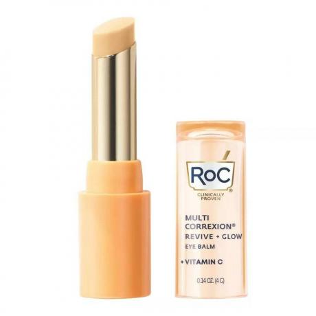 RoC Multi Correxion Revive and Glow C-vitamiini silmaalune palsam, oranž ja kuldne keeratav pulk läbipaistva oranži korgiga küljel valgel taustal