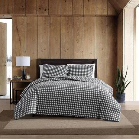 Un lit avec l'ensemble de couette Queen Eddie Bauer noir et blanc dans une chambre à panneaux en bois