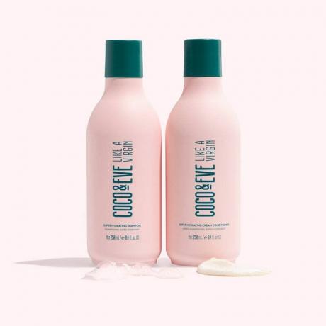 Conjunto de Shampoo e Condicionador Super Hidratante Coco + Eve: Dois frascos de shampoo rosa com tampas verdes e texto verde em um fundo rosa claro