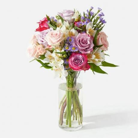 UrbanStems The Unicorn bouquet de fleurs rose, violet et blanc dans un vase transparent sur fond gris clair