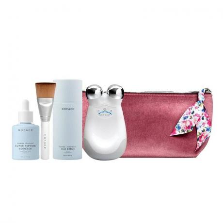 Рутинната грижа за кожата NuFace Trinity Supercharged, включваща четири продукта от марката, заедно с розова чанта за грим на бял фон