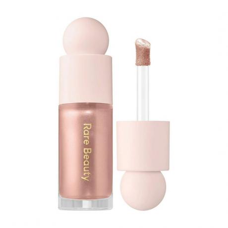 Rare Beauty Positive Liquid Light Luminizer ružičasti zlatni highlighter s dječjim ružičastim poklopcem i štapićem na bijeloj pozadini
