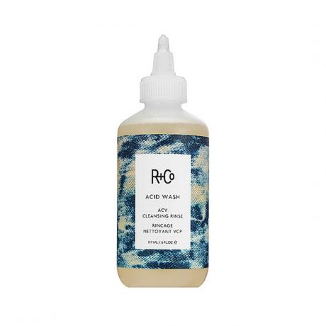 Напівпрозора пляшка R+Co Acid Wash ACV Cleansing Rinse із блакитним візерунковим логотипом і загостреним ковпачком на білому тлі